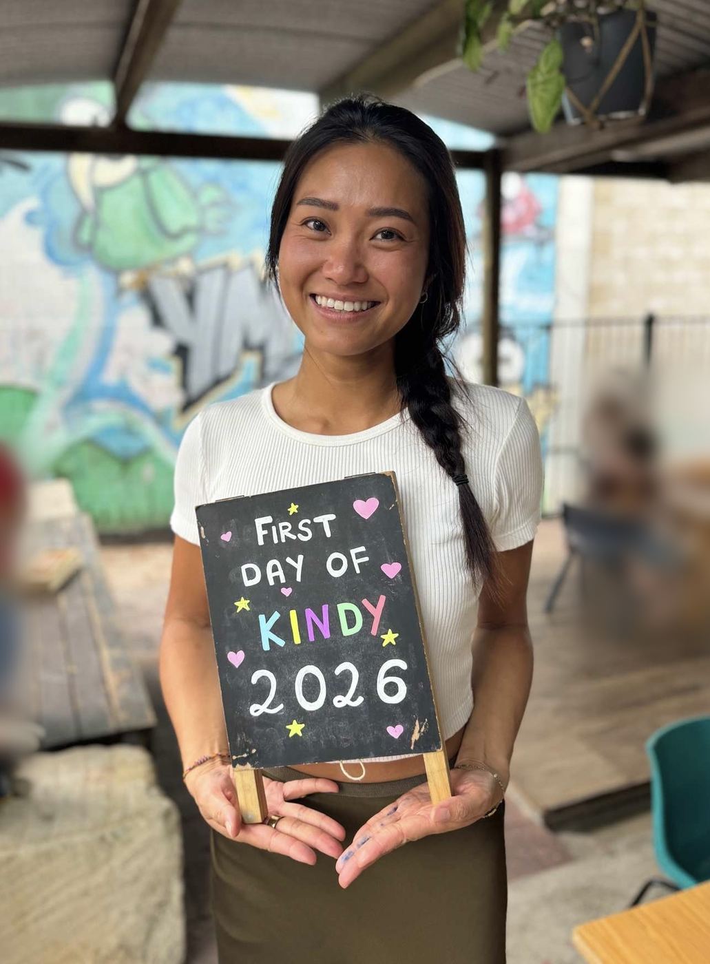 An holding a First Day of Kindy 2026 sign